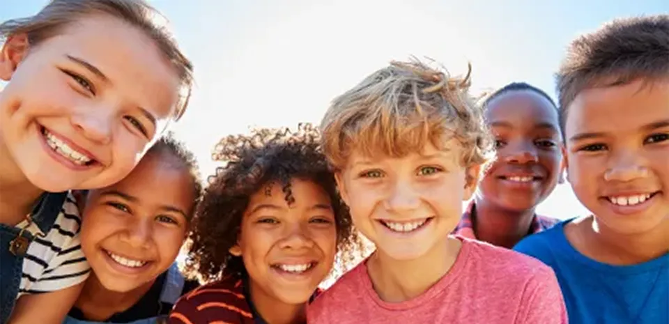 group of kids from diverse backgrounds smiling and playing outside together